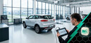 Специалист с диагностическим планшетом рядом с автомобилем